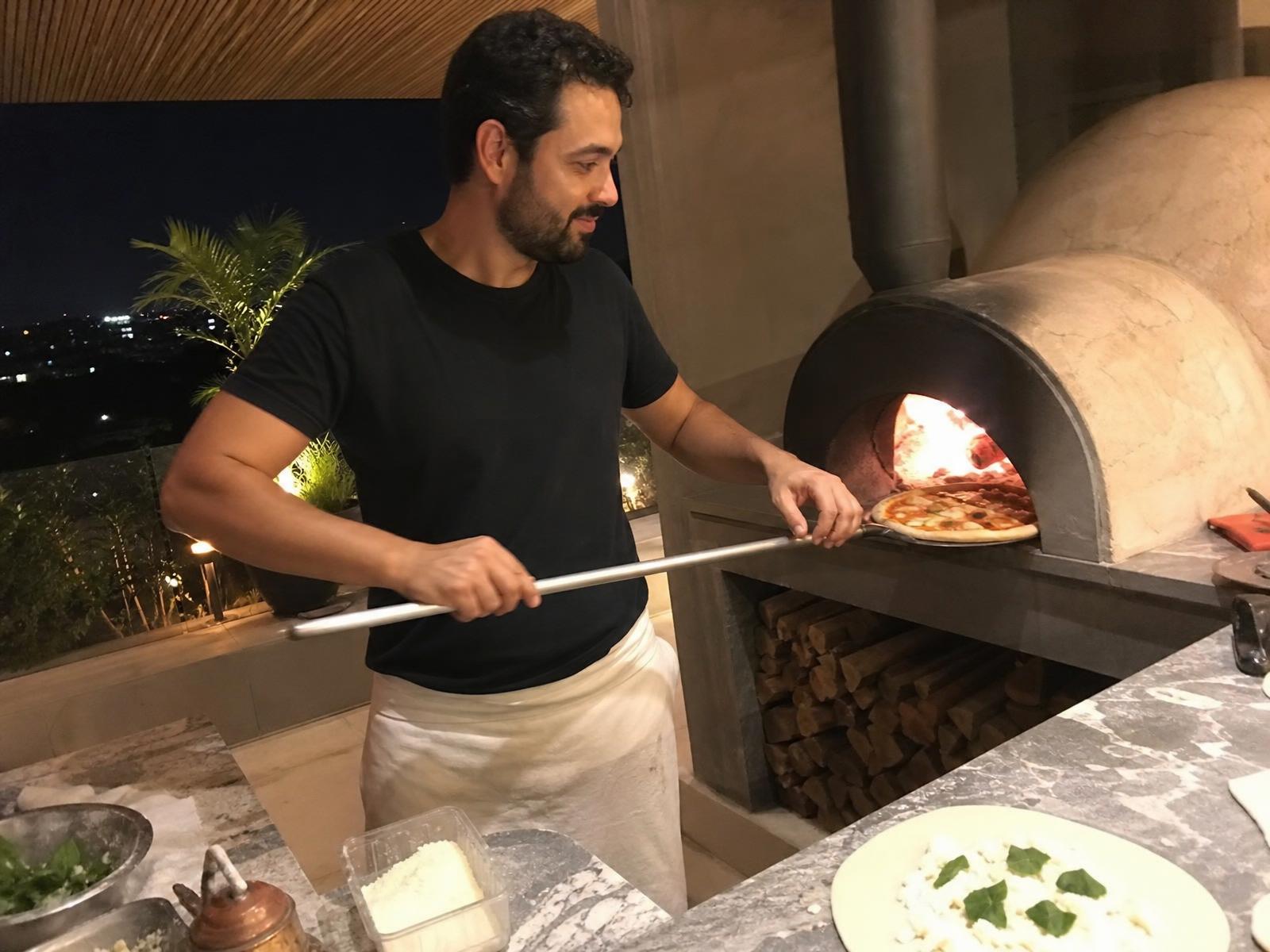 Pizzaiolo assando pizza em forno a lenha em festa de família